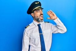 Middle age man with beard and grey hair wearing airplane pilot uniform shouting and screaming loud to side with hand on mouth. communication concept. 