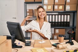 Young blonde woman working at small business ecommerce gesturing with hands showing big and large size sign, measure symbol. smiling looking at the camera. measuring concept. 