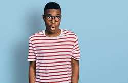 Young african american man wearing casual t shirt and glasses afraid and shocked with surprise expression, fear and excited face. 