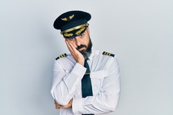 Young hispanic man wearing airplane pilot uniform thinking looking tired and bored with depression problems with crossed arms. 