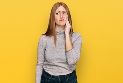 Young irish woman wearing casual clothes touching mouth with hand with painful expression because of toothache or dental illness on teeth. dentist 