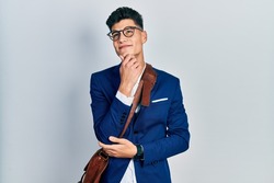 Young hispanic man wearing business clothes with hand on chin thinking about question, pensive expression. smiling with thoughtful face. doubt concept. 