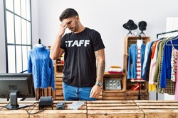 Young hispanic man working at retail boutique tired rubbing nose and eyes feeling fatigue and headache. stress and frustration concept. 