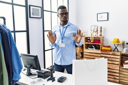 Young african man working as manager at retail boutique moving away hands palms showing refusal and denial with afraid and disgusting expression. stop and forbidden. 
