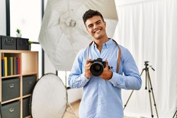 Young hispanic man photographer using professional camera at photography studio