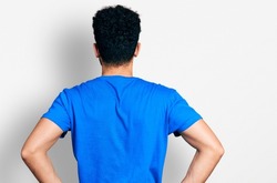 Young arab man with beard wearing casual blue t shirt standing backwards looking away with arms on body 