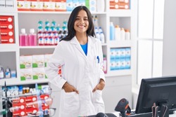 Young hispanic woman pharmacist smiling confident standing at pharmacy
