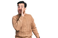 Young hispanic man wearing casual clothes hand on mouth telling secret rumor, whispering malicious talk conversation 