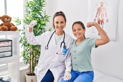 Woman and girl doctor and patient doing power gesture at clinic