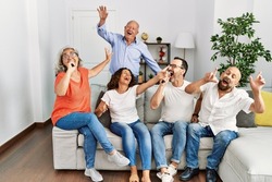 Group of middle age friends having party singing song using microphone at home.