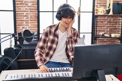 Young hispanic man musician composing song at music studio