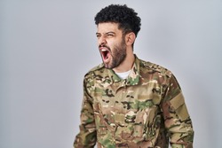 Arab man wearing camouflage army uniform angry and mad screaming frustrated and furious, shouting with anger. rage and aggressive concept. 