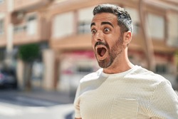 Young hispanic man standing with surprise expression at street