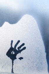 A palm print on a frozen window pane. human hand