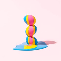 Easter eggs stacked  on top of each other with punchy paint dripping against pink background. Blue, yellow and pink color poured over eggs. Creative holiday layout. Minimal raw food concept.