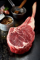 Piece of raw rib eye tomahawk steak in close up view on dark countertop