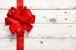 Decorative red ribbon and bow on a background of white painted rustic boards with copyspace
