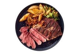 Top view of delicious grilled beef steak and rustic potatoes wedges with vegetable salad served on plate on white background