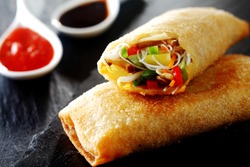 Crispy golden fried vegetable spring rolls with fresh ingredients served with soy and sweet and sour sauce in an oriental restaurant