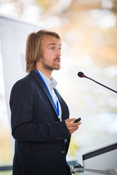 Handsome young man giving a speech at a conference