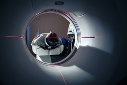 Senior man going through a Computerised Axial Tomography (CAT) Scan medical test, examination in a modern hospital (colour toned image; shallow DOF)