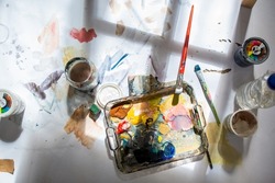 Palette and paint brush in artist hands. Artist paints oil picture with paint brush in hand palette close-up. Artist painting holding palette and paint brush in hand. Artists paintbrush with palette.