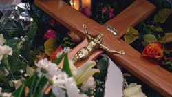 Christian Catholic Fresh Grave with Wooden Burial Crucifix Covered with Flowers and Funeral Wreath