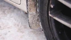 Clumps of Frozen Snow Slush Collected on Car Wheel Mud Flap Mudguard