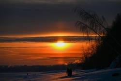 red sunset on the bank of a frozen river. The photo was taken at dusk with the rays of the sun
