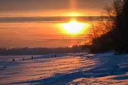 red sunset on the bank of a frozen river. The photo was taken at dusk with the rays of the sun