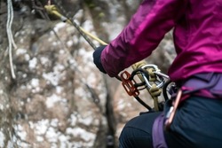 Climbing equipment, ropes, carabiners, harness, belay, close-up of a rock-climber put on by a girl, the traveler leads an active lifestyle and is engaged in mountaineering.