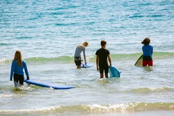 Surf beginners going to surf on sea waves. Active lifestyle, kids outdoor water sport Surfing Lessons and swimming activity in surf camp. Summer vacation