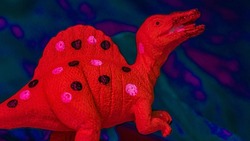 A plastic dinosaur with a trippy background