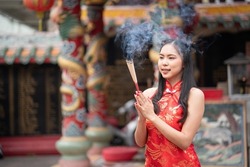 Woman lighting incense sticks to pay homage to Chinese New Year