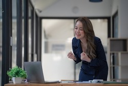 Shot of a young businesswoman cheering while working on a laptop in an office.
