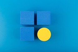Blue toy cubes and yellow circle on dark blue background. Concept of individuality, being different from others, leadership or unique ideas 