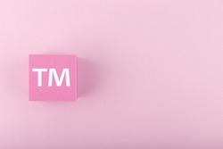 White TM trademark sign on pink figure on pink background with copy space. Minimal trendy concept of intellectual property registration and protection