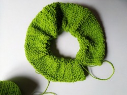 Unfinished circlular pattern crochet scrunchie project isolated on white. Double crochet application on making scrunchie. Green crochet yarn for making scrunchie. Handmade crochet scrunchie progress