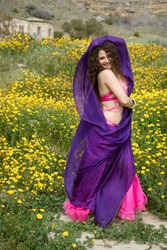 Woman performing belly oriental dancing wearing colored costume. Dancing outdoors