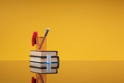 School accessories as a back to school concept. Stapler and writing accessories on a stack of old books as a background with free space for the website of a school, institute, university