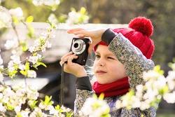 Toddler girl (6 years) taking photo of flowers in a spring. Cherry tree flowers in a spring.