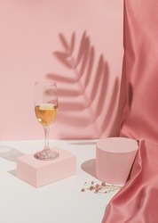 Romantic pastel pink Valentine's Day composition with wine glass, satin curtain and shadow. Suitable for Product Display and Business Concept. Modern aesthetic.