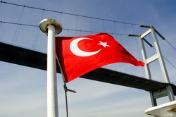 Turkish flag flutter in the wind in front of the bridge with blue sky in background