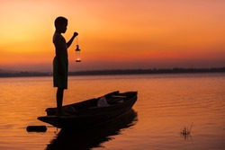 Young boy Standing on boat with hand hold Lantern on Silhouette  sky background , Silhouette,people, boy,man