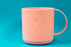 Pink cup on a blue background. A monochromatic cup close-up.
