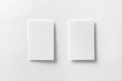 Mockup of two vertical business cards at white textured paper background.