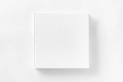 Mockup of closed blank square book at white textured paper background.