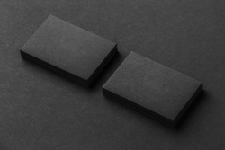 Mockup of two blank business cards stacks at black textured background.