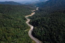 long road curved in valley connecting countryside in the rainforest and the verdant hill forest at northernmost part of Thailand aerial view from drone shot 