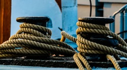 Maritime hemp rope moorings on a black cast iron bollard on the dock.